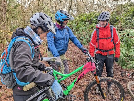 Three people talking with the one in the middle pointing at a colourful bike.